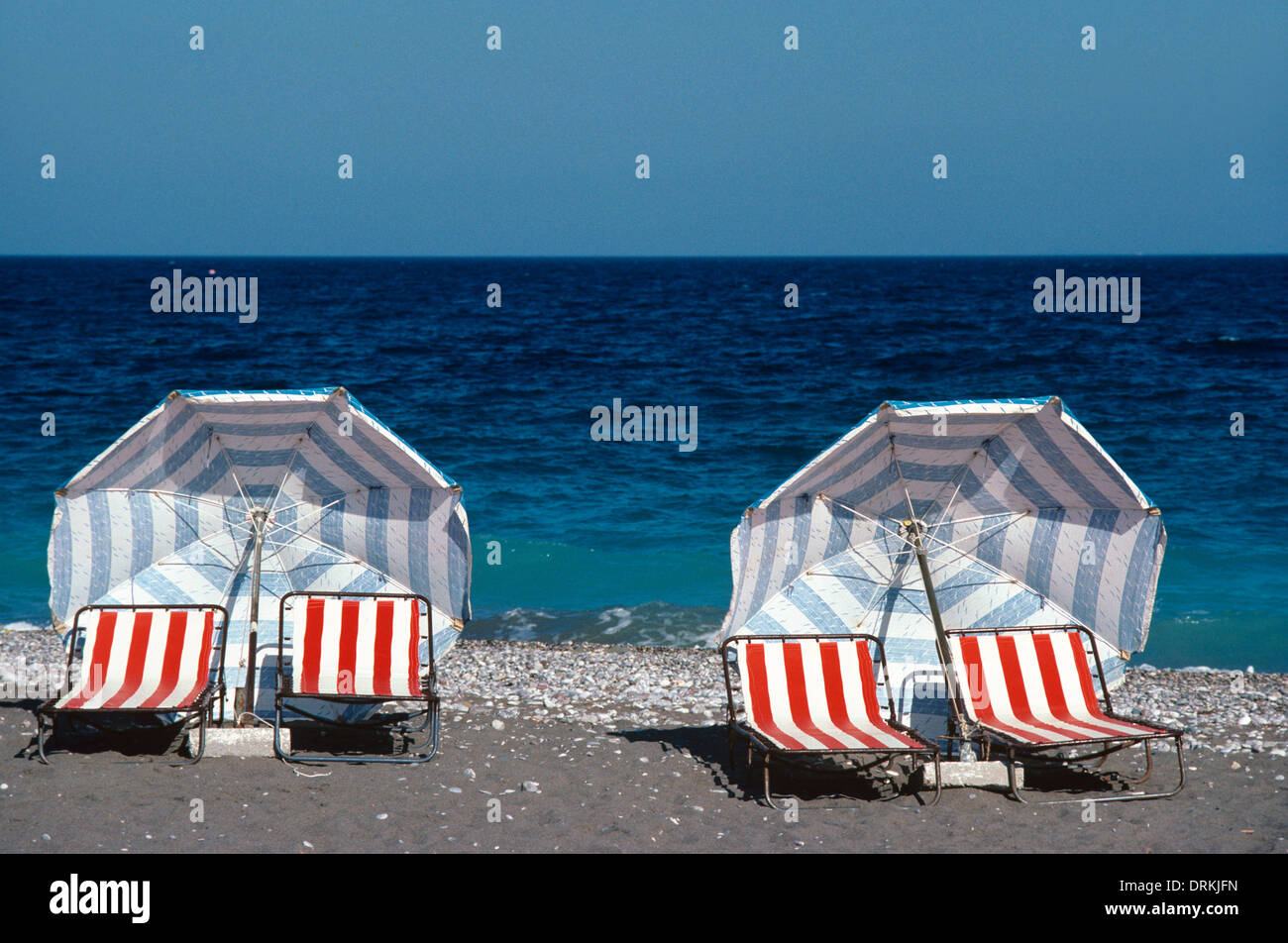 & Strand Liegestühle Sonnenschirme oder Sonnenschirme am menschenleeren Strand & Mittelmeer Rhodos Griechenland Stockfoto