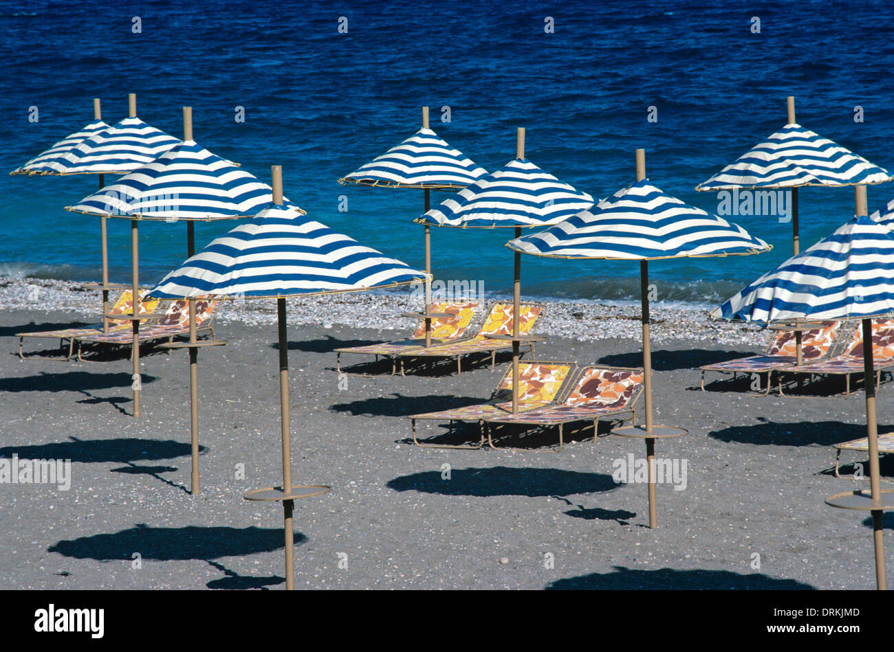 Muster der Sonnenschirme Sonnenschirme & Sonnenliegen auf einsamen Strand & Mittelmeer Rhodos Griechenland Stockfoto