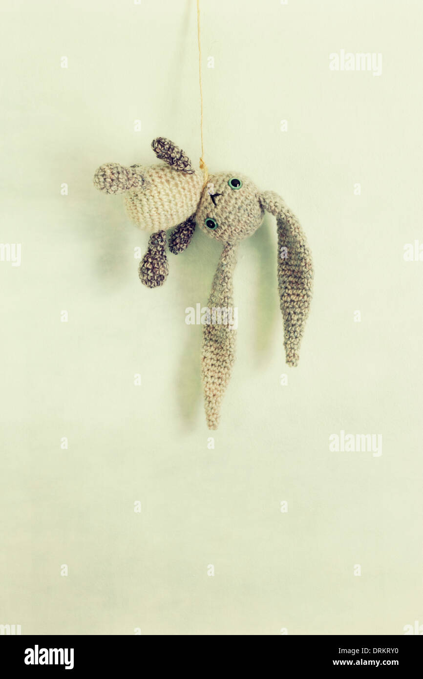 Eine gehäkeltes Spielzeug Hase mit langen Schlappohren hängt von einer Zeichenfolge/Schlinge. Stockfoto