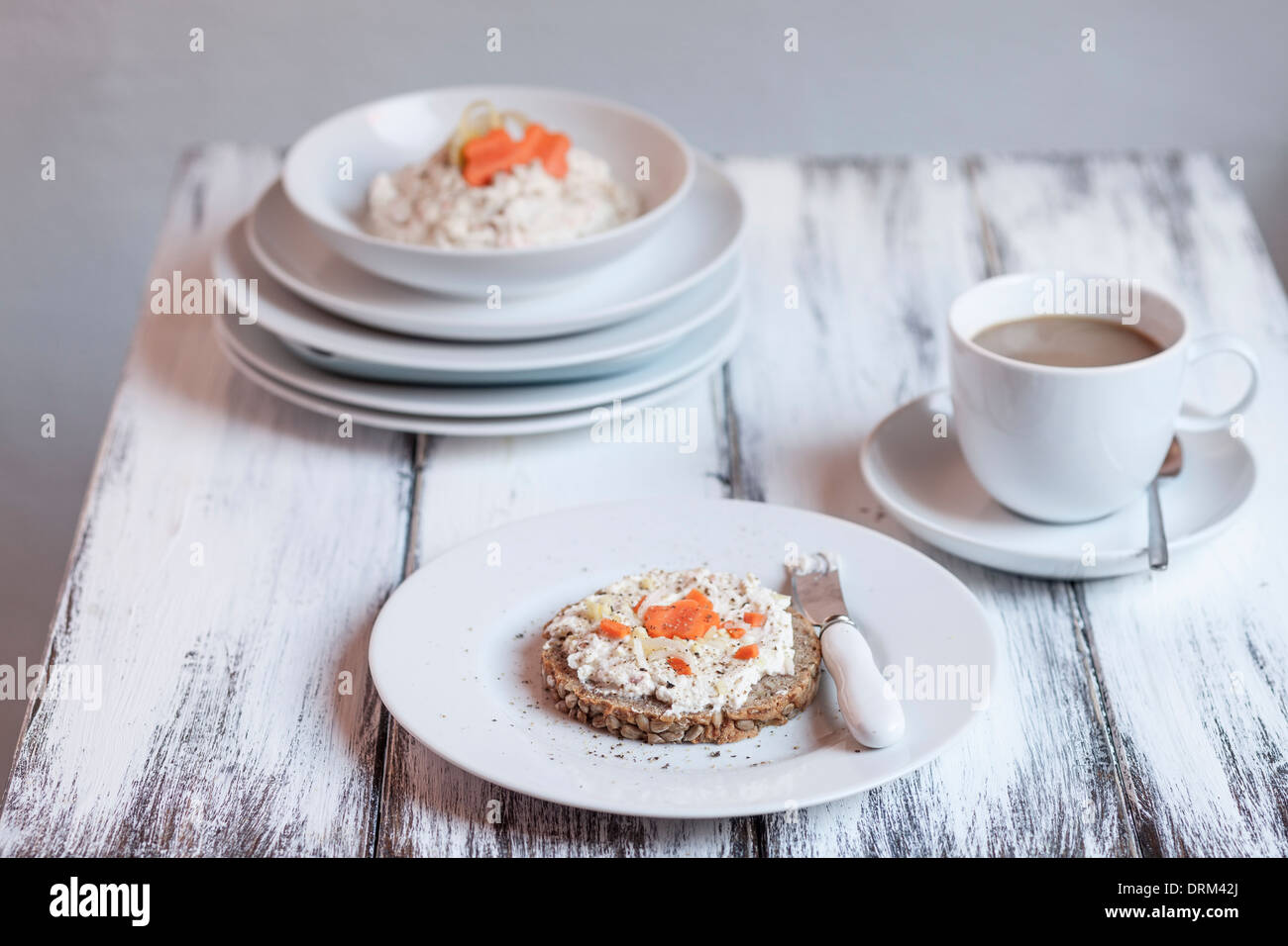 Deutsche dunkles Mehrkorn Brot mit Quark und Karotten, Tasse Kaffee auf Holztisch Stockfoto