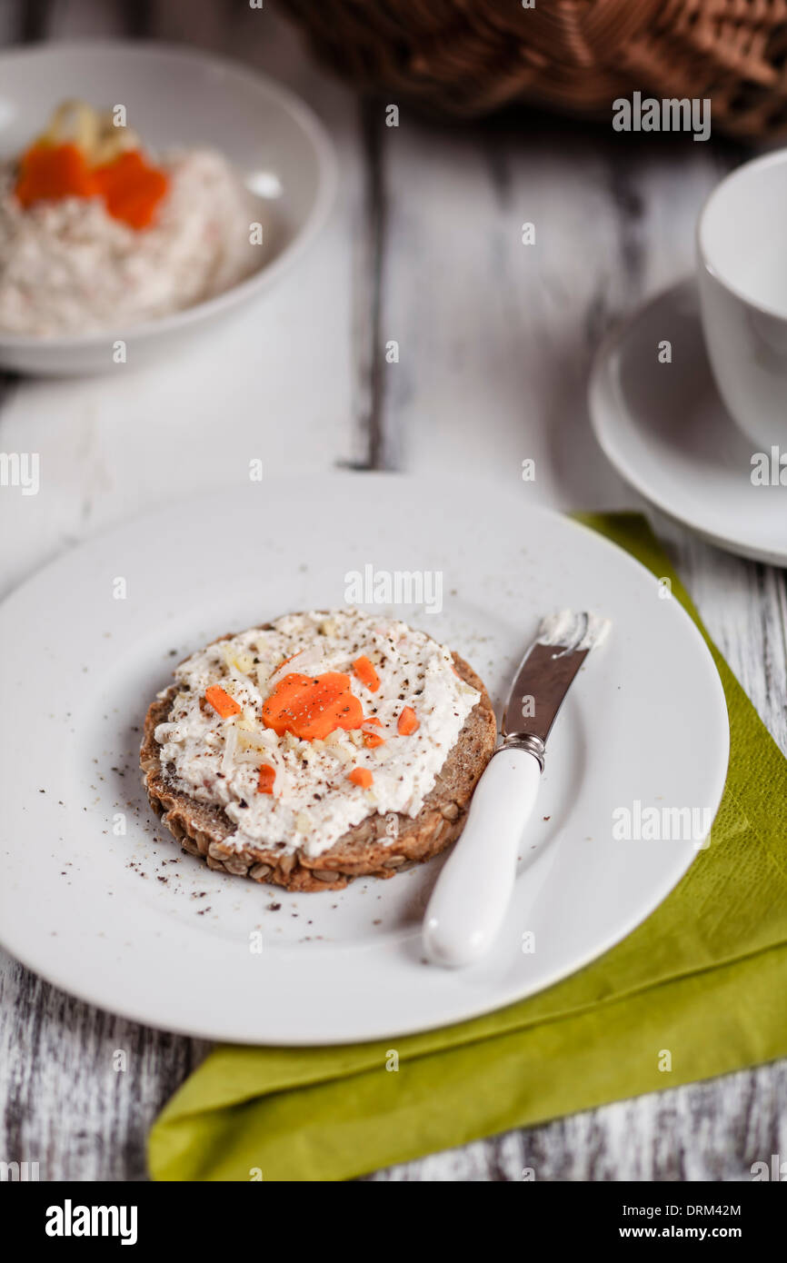 Deutsche dunkles Mehrkorn Brot mit Frischkäse und Karotten, Tasse Kaffee Stockfoto