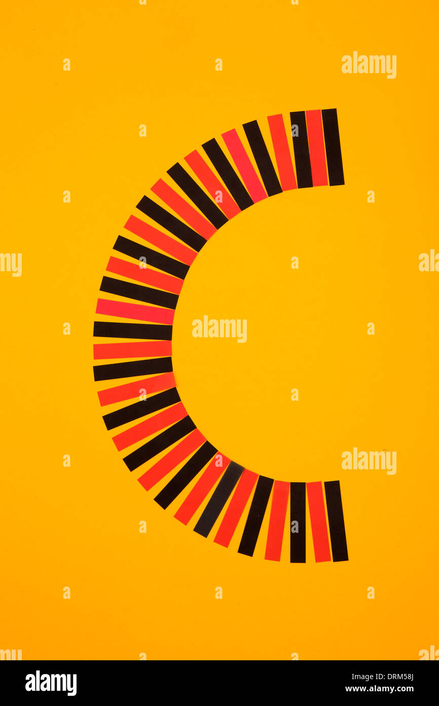 Buchstabe "C" gebildet aus rotem und schwarzem Papier Streifen auf gelbem Grund, Studio gedreht Stockfoto
