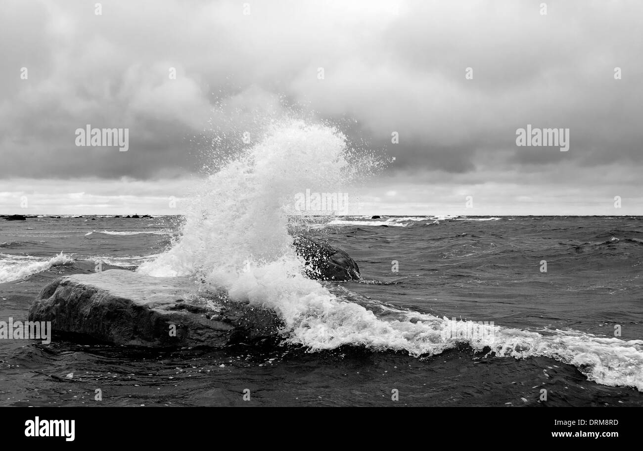Weiße Wellen schlagen einen großen Felsen im Meer Stockfoto