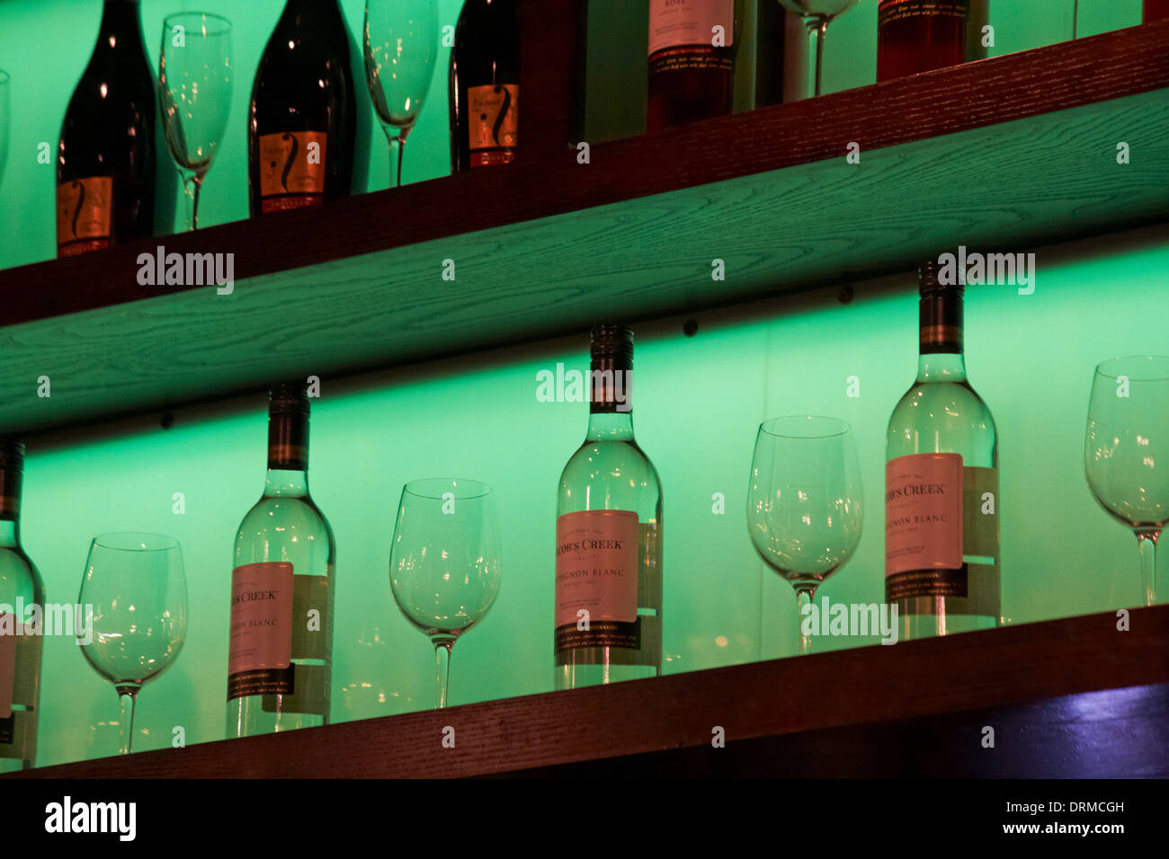 Flaschen Jacobs Creek Sauvignon Blanc Weißwein und Weingläser in Regalen mit grüner Beleuchtung Stockfoto