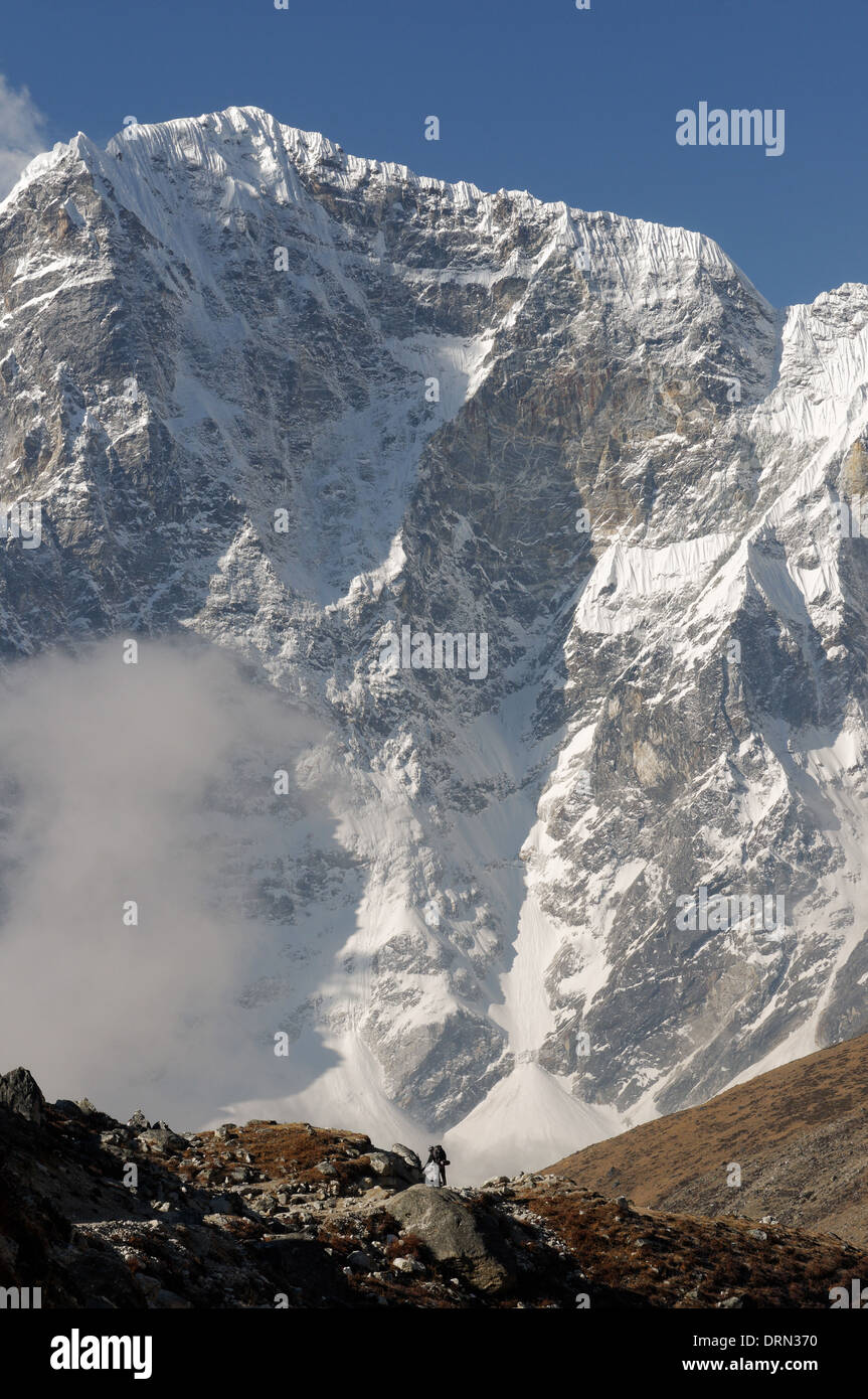 Die kleine Figur eines Trekker wird durch die Ostwand des Taboche auf dem Everest Base Camp Trek in den Schatten gestellt Stockfoto