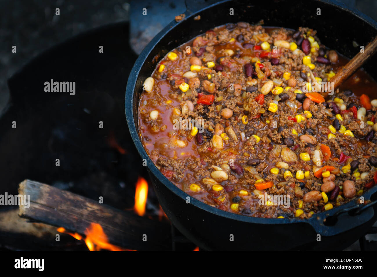 Großen gusseisernen Topf mit würzigen Chili Kochen über dem Lagerfeuer Stockfoto