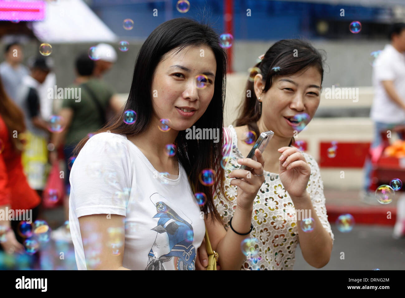 Manila, Philippinen. 30. Januar 2014. Frauen gehen in Chinatown Manila Begegnung Bläschen von einem Straßenhändler auf 30. Januar 2014. Glücksbringer, Obst, Straßenkünstler und Feuerwerkskörper wurden gesehen, um Chinatown in Manila, ein Tag vor der Feier das chinesische Neujahr, das Jahr des Pferdes. Foto: Mark Cristino/Alamy Live-Nachrichten Stockfoto