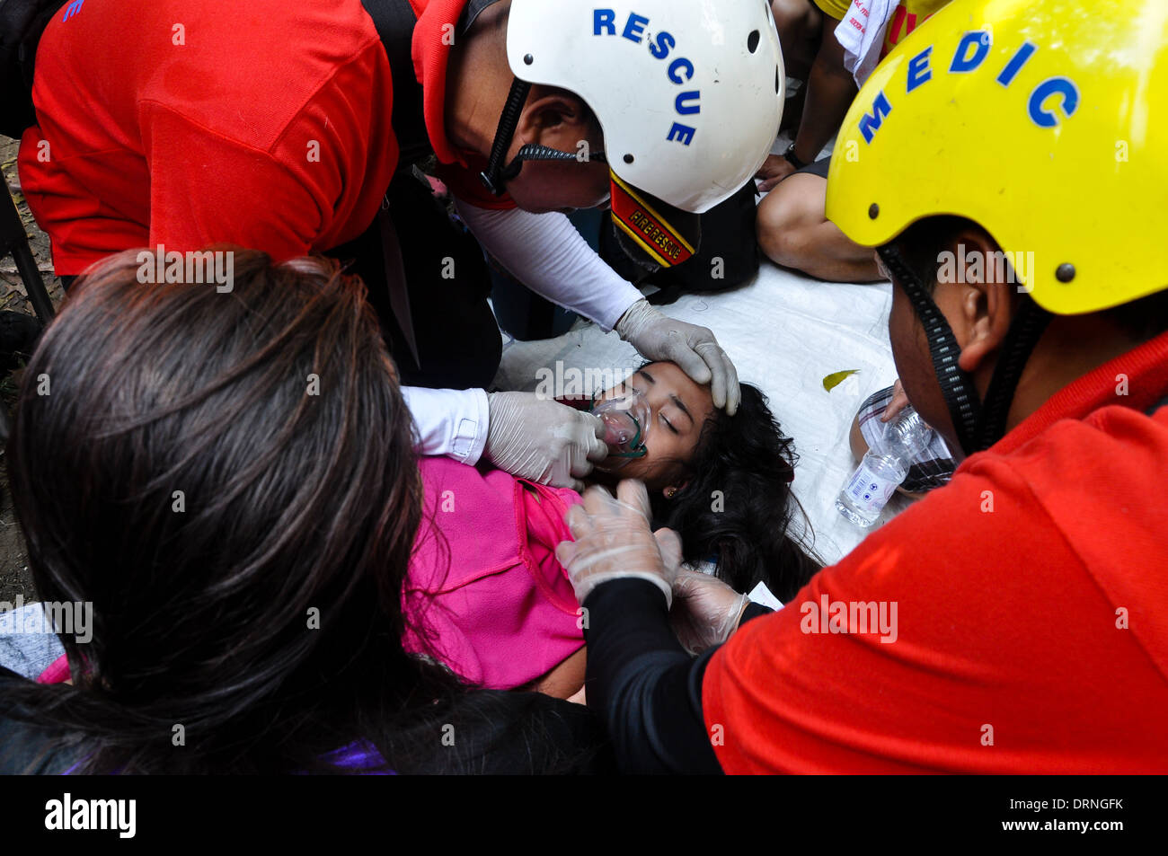 Medizinisches Personal liefern Sauerstoff, ein Mädchen, das während der Prozession des schwarzen Nazareners in Manila in Ohnmacht gefallen. Stockfoto