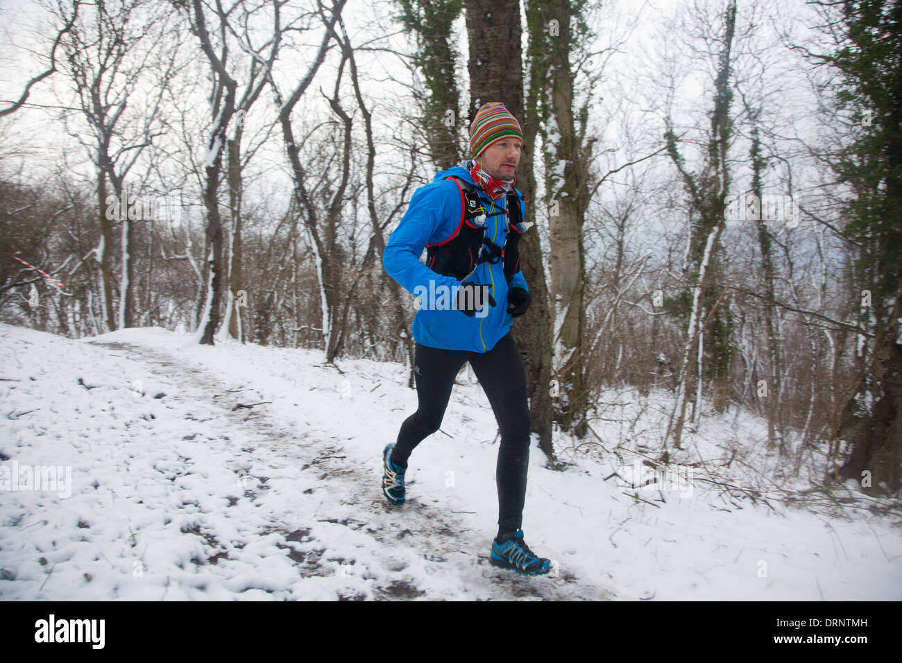 Ein Läufer macht seinen Weg auf den verschneiten Pfad durch den Wald in der Nähe von Hammershus. Stockfoto