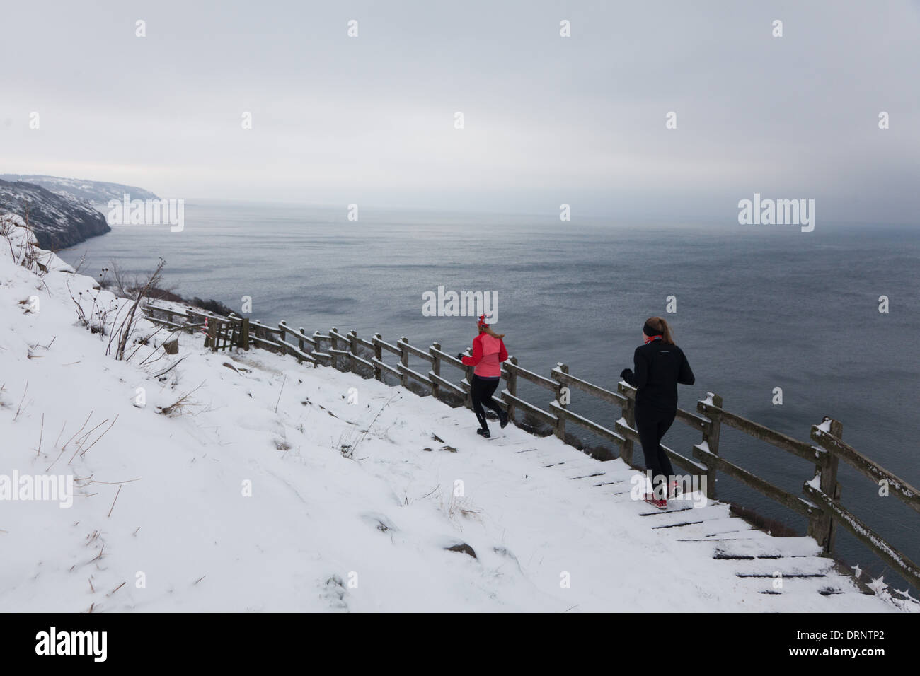 Zwei Läufer finden ihren Weg auf einen verschneiten Weg in Richtung Meer unterhalb von Hammershus. Stockfoto