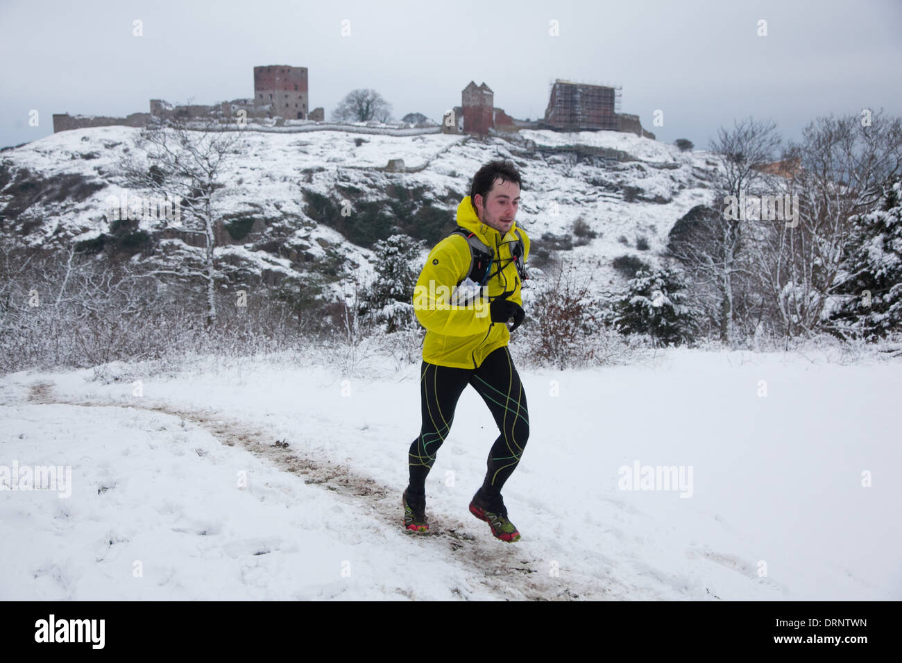 Ein Läufer macht seinen Weg über den Hügel mit Hammershus im Hintergrund. Stockfoto