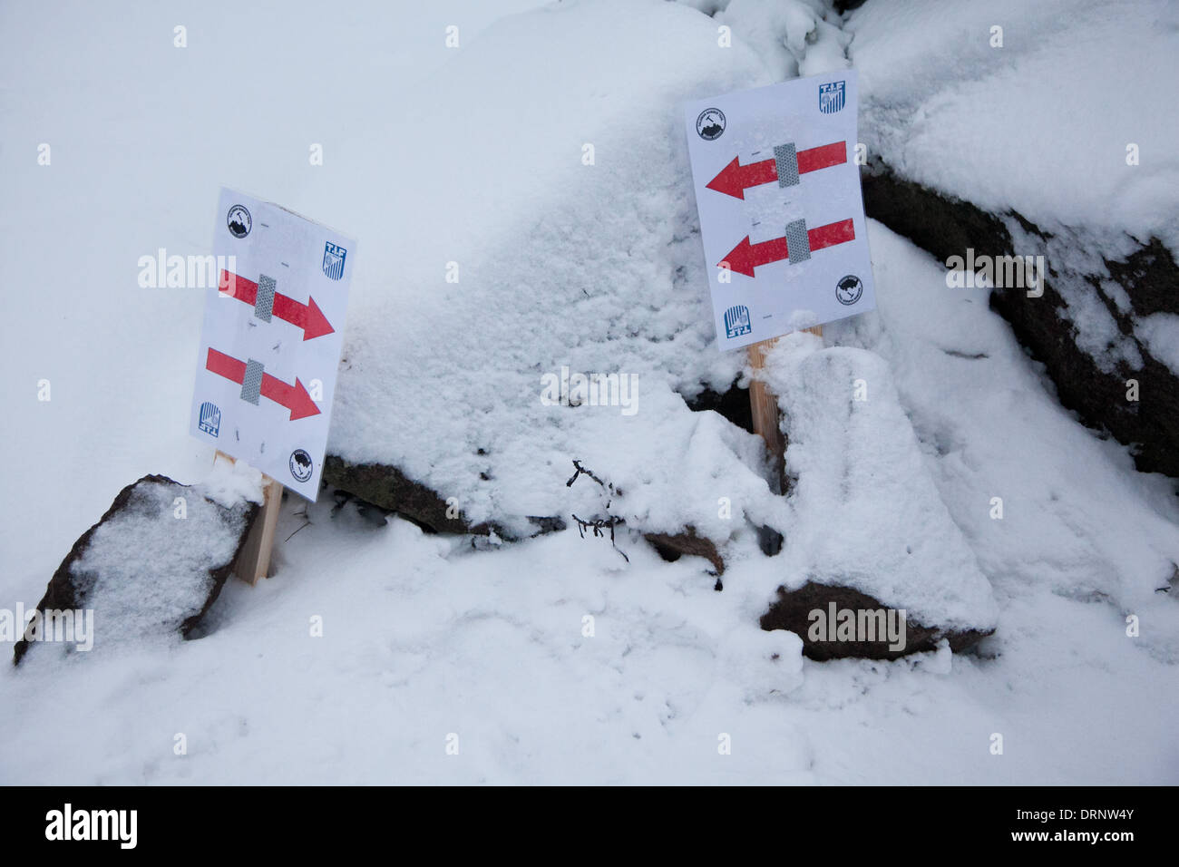 Zeichen mit roten Pfeilen im weißen Schnee zeigen die Läufer welchen Weg - beide Richtungen in diesem Fall ausgeführt. Stockfoto