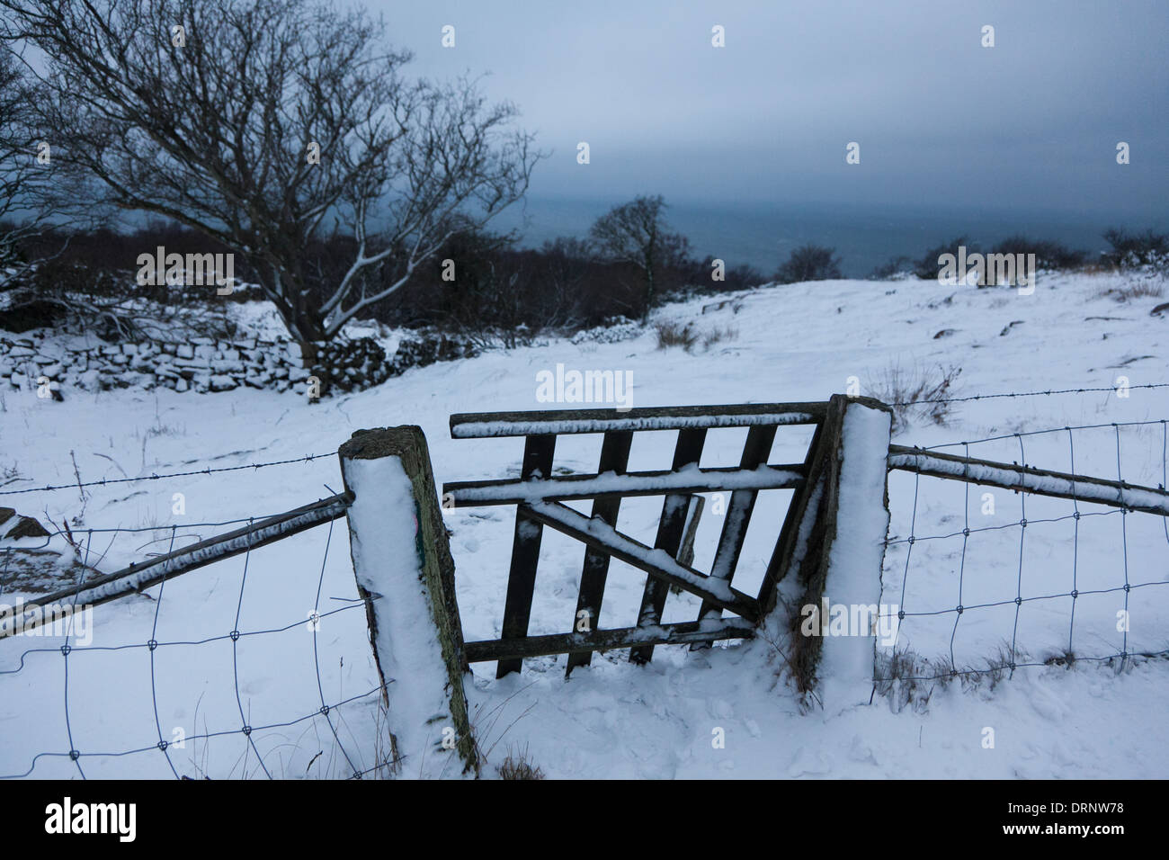 Ein Zaun und ein Tor in der Abenddämmerung auf der Insel, im Schnee bedeckt Winter ist endlich da. Stockfoto