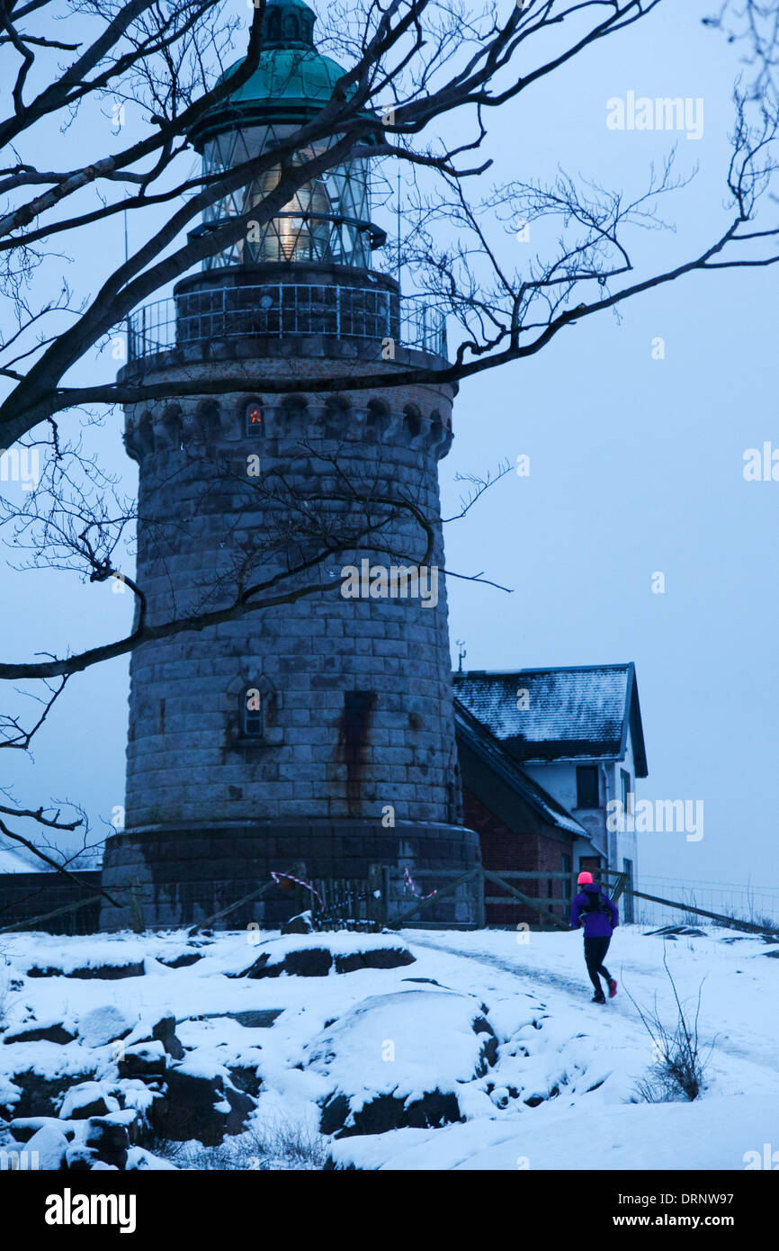 Ein Läufer macht ihren Weg den Hügel vom Meer hinauf und oben auf dem Leuchtturm am Hammer Knude. Stockfoto