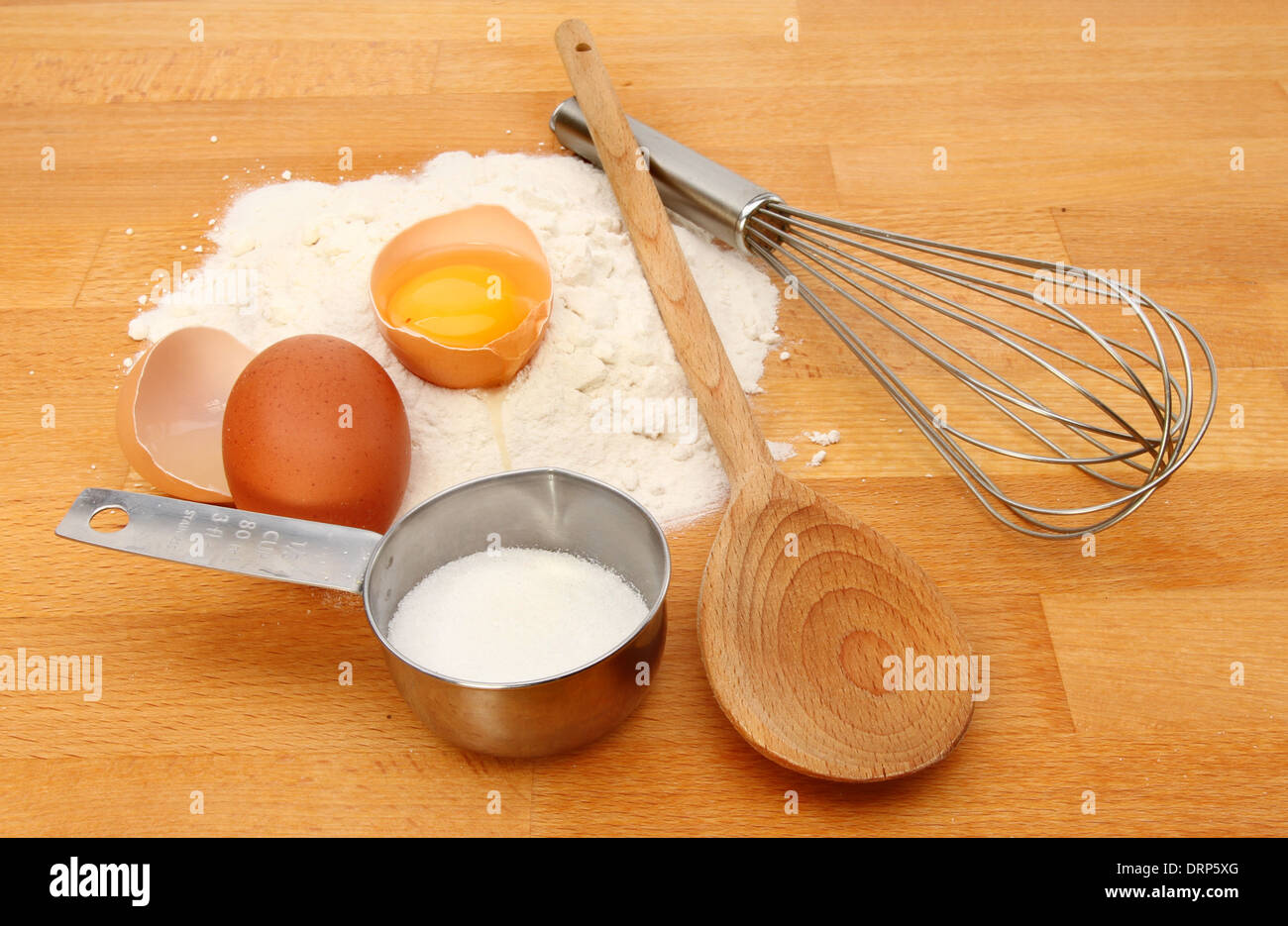 Backen, Zutaten, Mehl, Ei und Zucker mit einem Kochlöffel und Schneebesen auf einer Küchenarbeitsplatte Stockfoto
