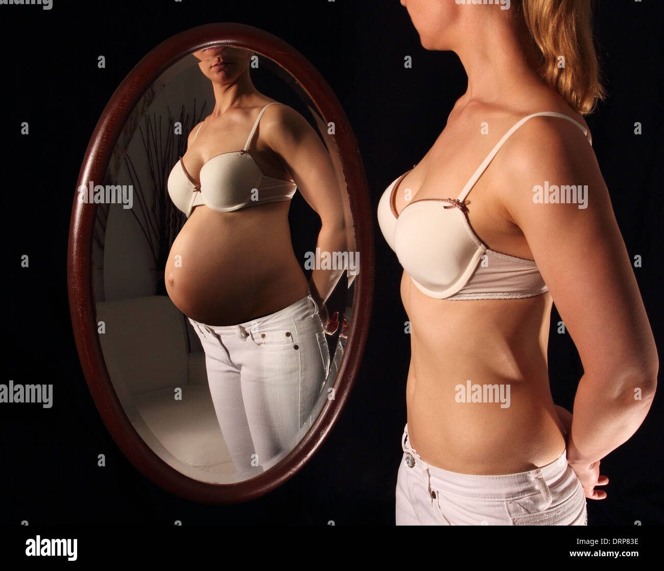 Frau, die sich Schwangere in einem Spiegel zu sehen Stockfoto