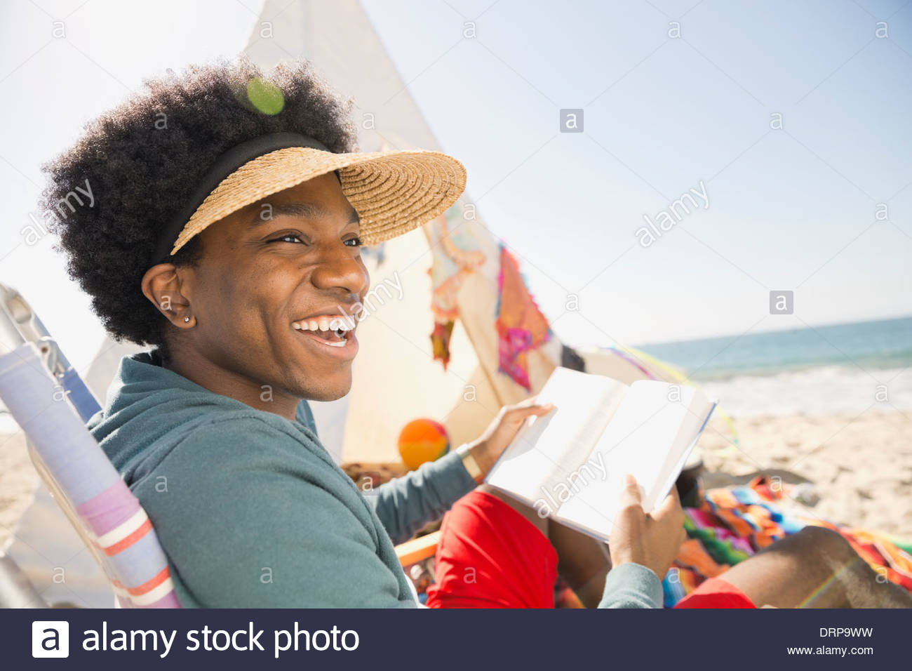 Fröhlicher Mensch Buch am Strand lesen Stockfoto
