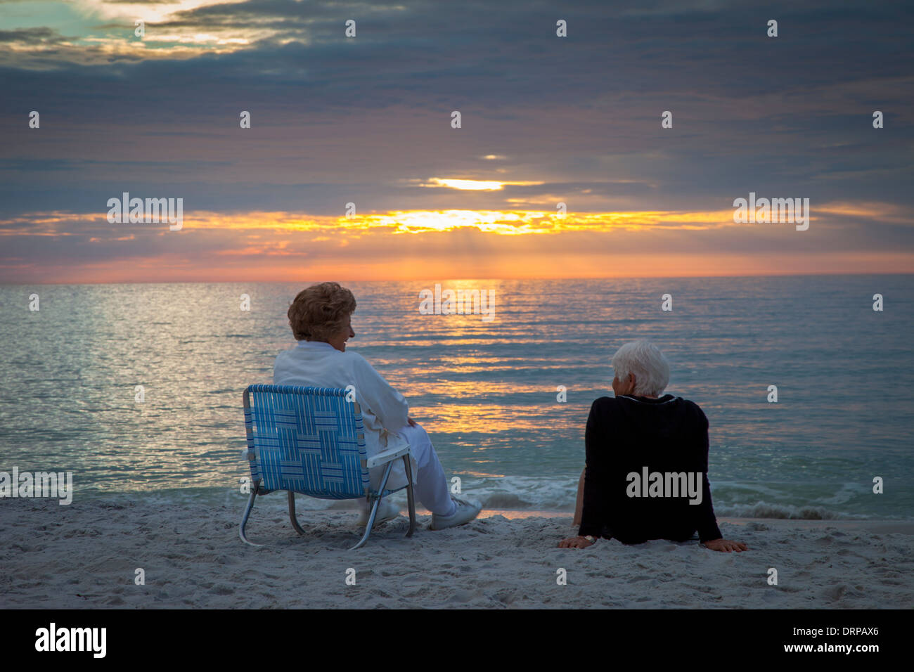 Zwei ältere Frauen, die einen Sonnenuntergang am Strand von Naples, Florida, USA Stockfoto