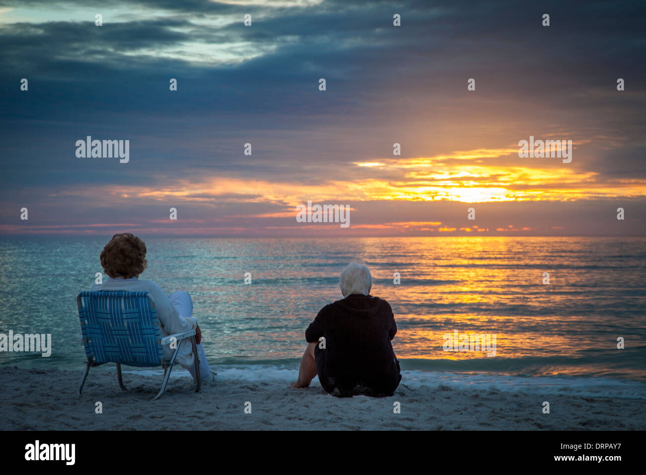 Zwei ältere Frauen, die einen Sonnenuntergang am Strand von Naples, Florida, USA Stockfoto