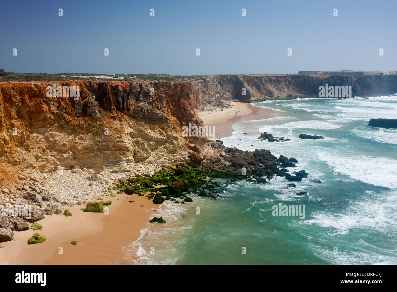 Praia Tonel Strand ockerfarbenen Felsen und rauen Meer Fortaleza auf Klippen in Ferne Sagres Costa Vicentina Algarve Portugal Stockfoto