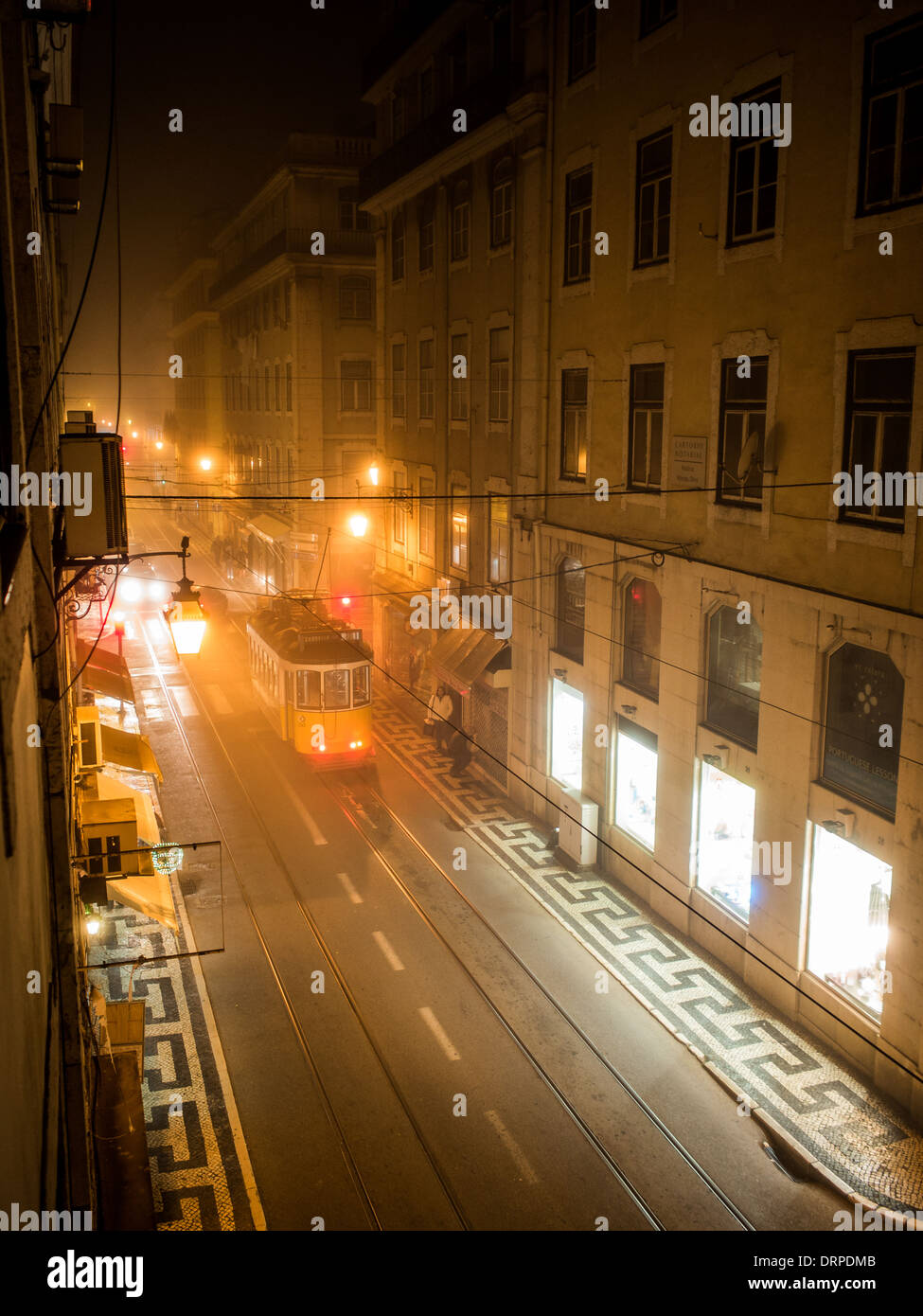 Eine Straßenbahn kreuzt die Innenstadt von Lissabon-Straße in Baixa Pombalina in einer nebligen Nacht Stockfoto