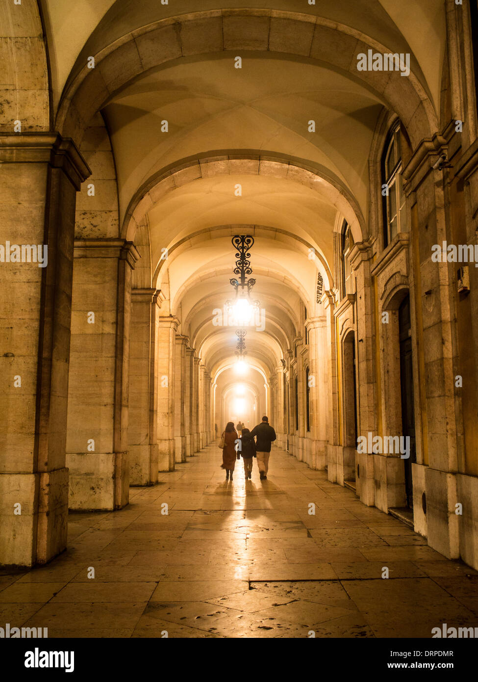 Die Leute laufen unter der Lissabonner Innenstadt-Arkade in einem nebligen Nacht Stockfoto