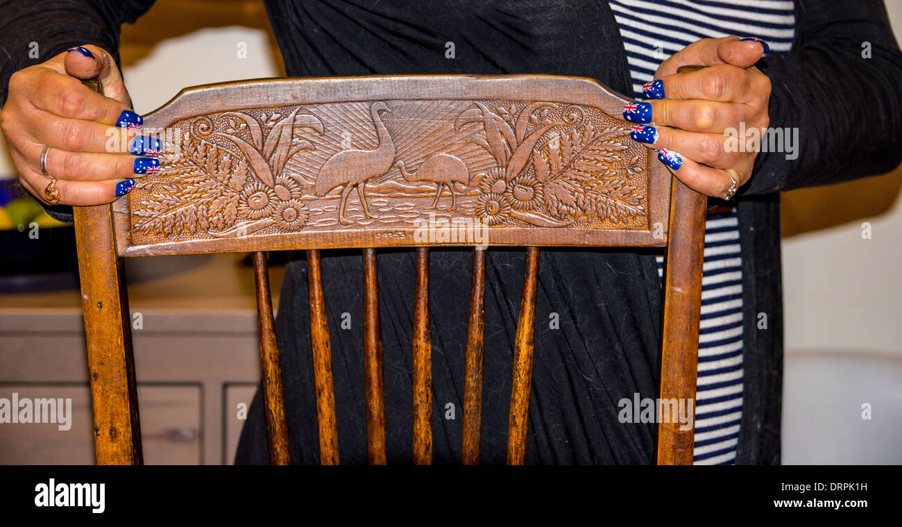 Australische Fahnen gemalt auf die Nägel der Hände, die auf einem antiken geschnitzten Holzstuhl mit einheimischen Tieren Stockfoto