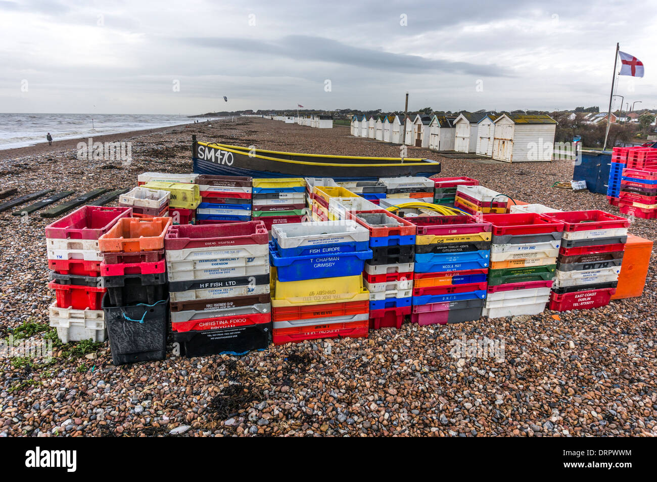 Gestapelte Kisten aus Kunststoff Fische, Boot und Strand Hütten auf Goring-by-Sea Pebble Beach, in der Nähe von Worthing, West Sussex. Stockfoto