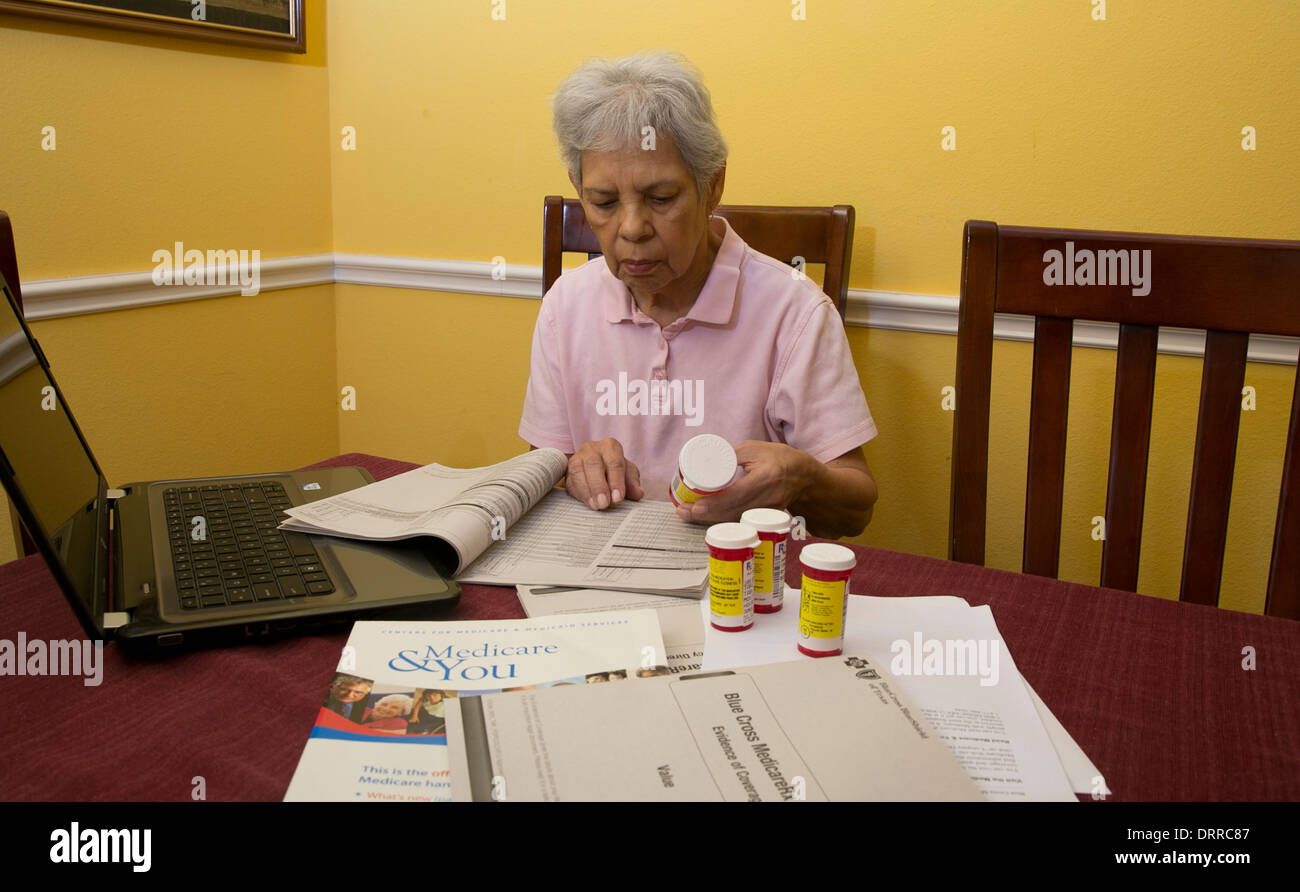 Hispanic 75 jährige Seniorin Frau Medicare Broschüre Broschüre liest und schaut auf ihre verschreibungspflichtigen Medikamenten Stockfoto