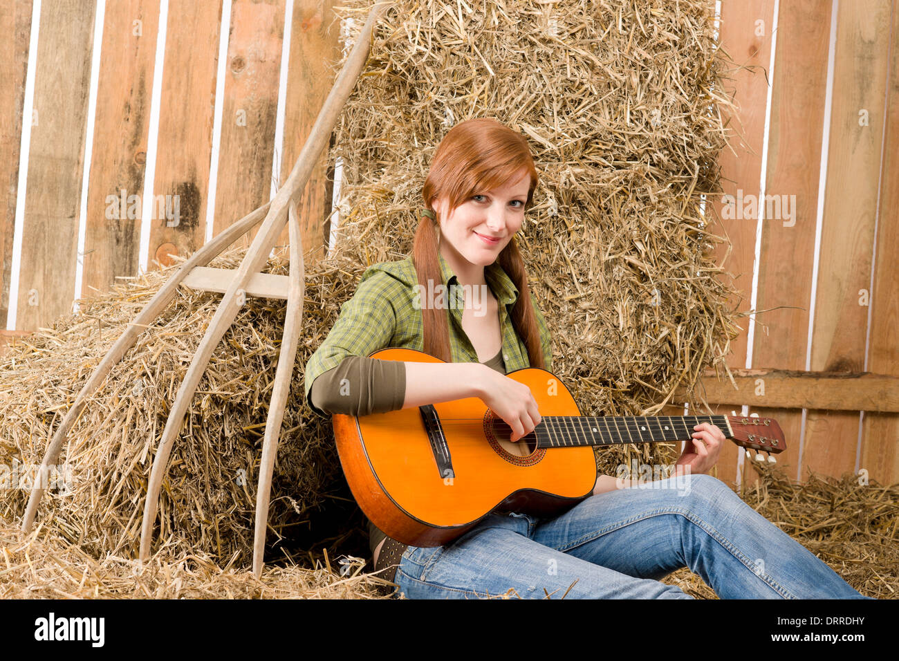 Junges Land Frau spielen Gitarre in der Scheune Stockfoto