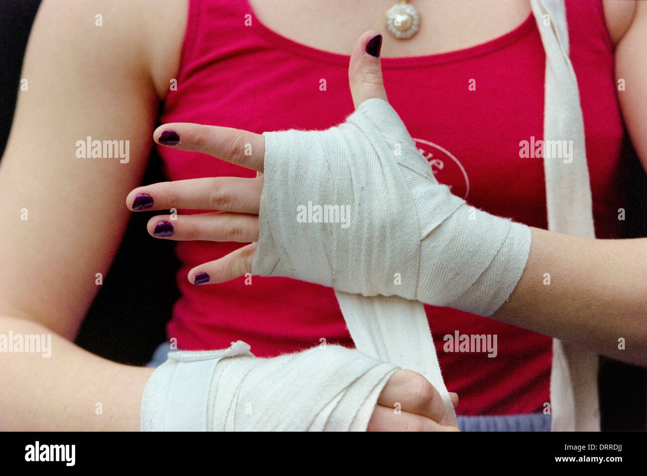 Eine Boxerin hüllt ihre Hände in Bandagen bevor ihre Boxhandschuhe anziehen Stockfoto