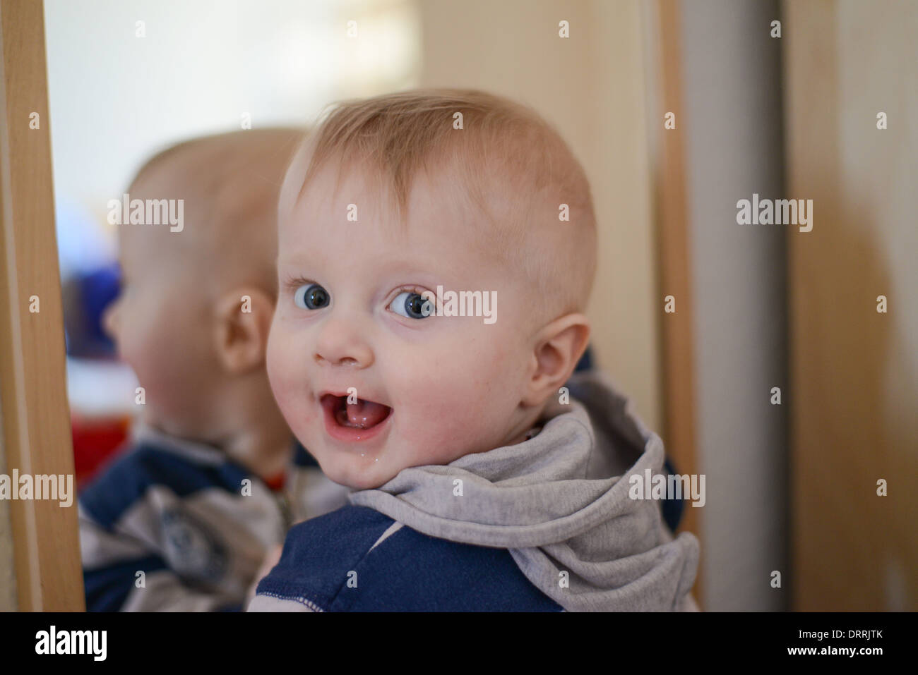Porträt eines acht Monate alten Baby Boy vor einem Spiegel in die Kamera schaut neugierig Stockfoto