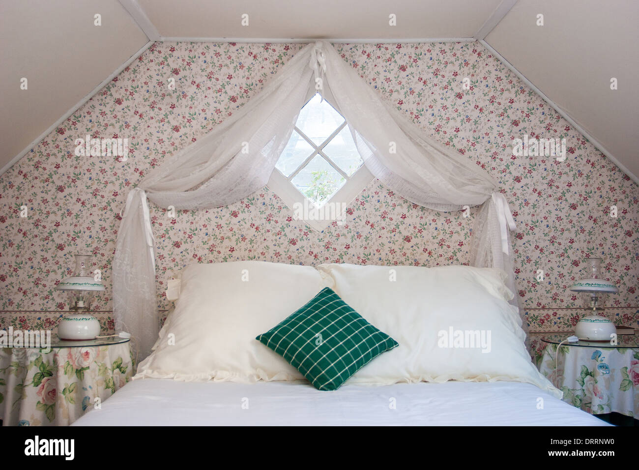 Symmetrische Dachgeschoss Schlafzimmer mit Vorhang Diamant Fenster  Blumentapete und schlichte Bettwäsche mit smaragdgrünen Kissen  Stockfotografie - Alamy