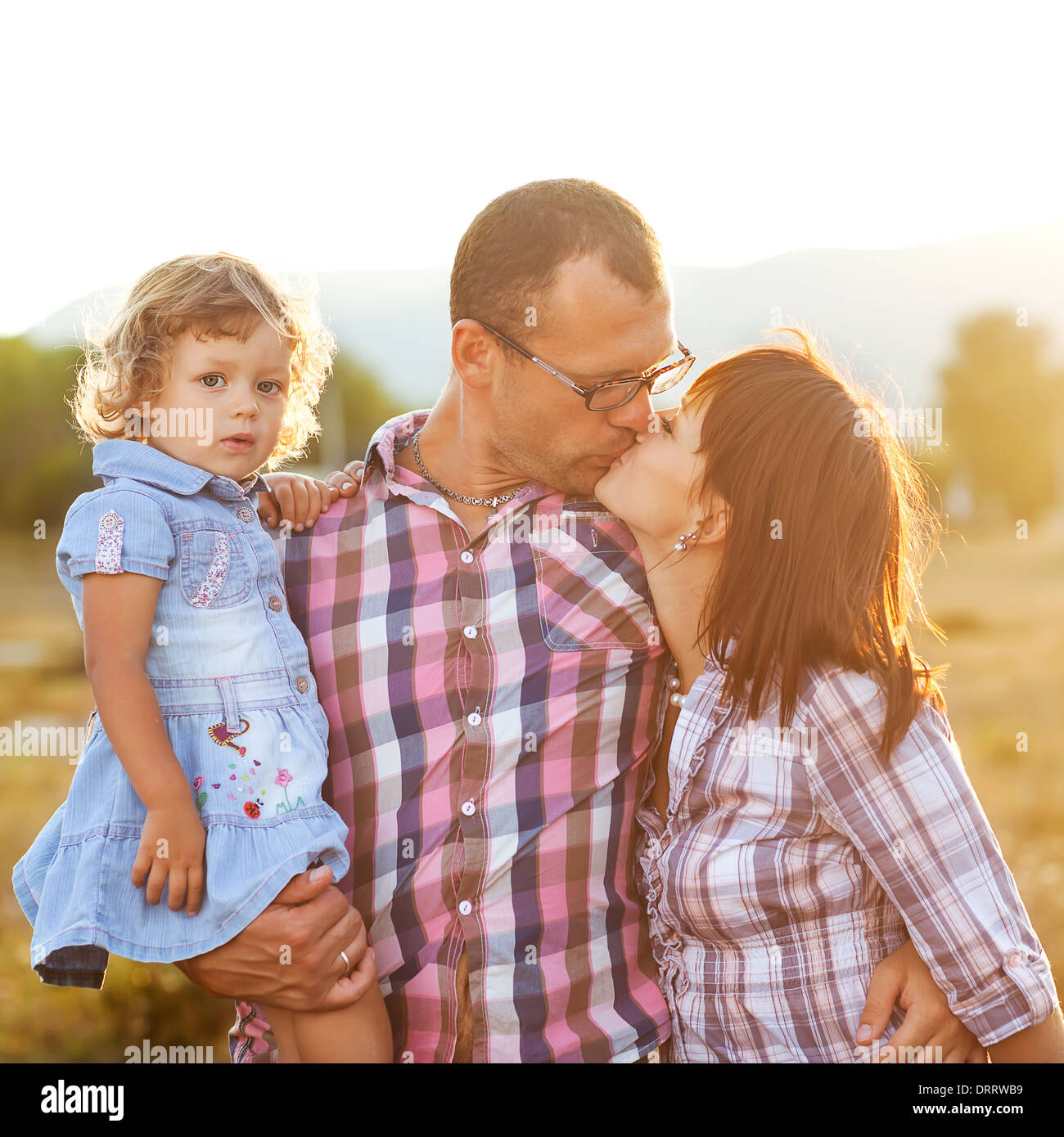 Glückliche Mutter, Vater und Tochter im Sonnenuntergang Stockfoto