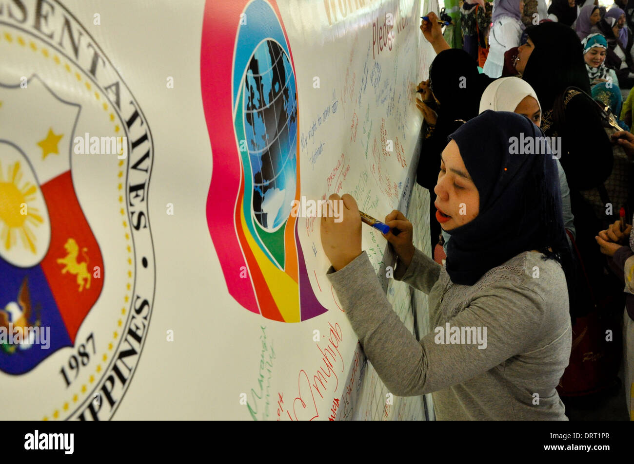 Muslimischen und nichtmuslimischen Frauen schreiben Zusagen in einer Wand während der Feier des Welttages Hijab in Quezon City. Stockfoto