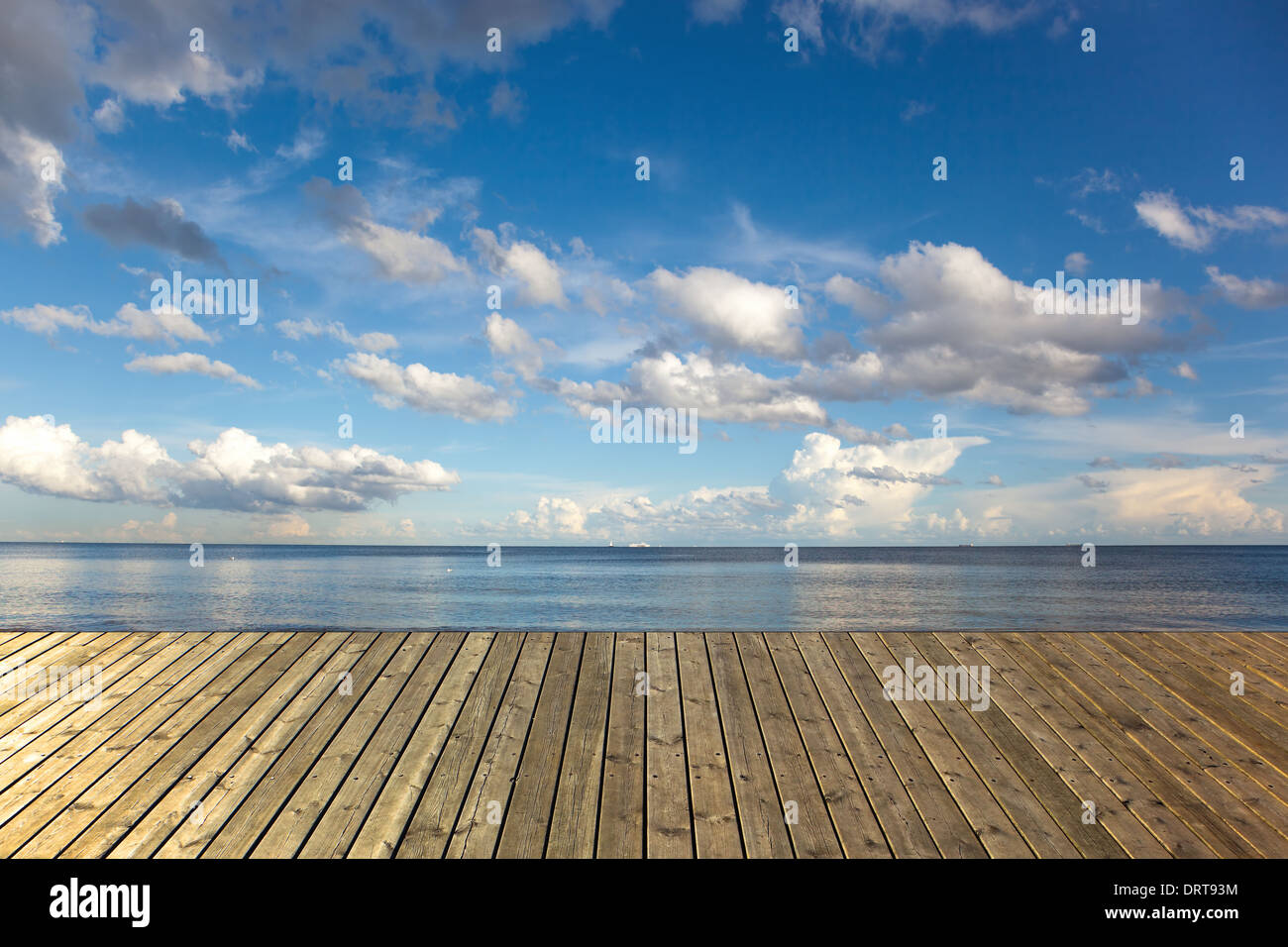 Leere Holzsteg auf einem Meer mit blauen Himmel und Wolken. Stockfoto