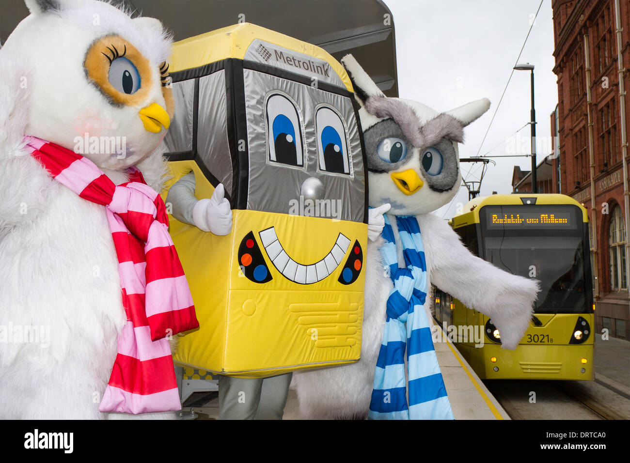 Furry Eule Maskottchen in Oldham, Manchester, Großbritannien, 1. Februar 2014. Stadtzentrum Maskottchen, Ollie und Millie am neuen Transport Link Oldham Central Station. Die metrolink Transport Expansion setzt sich mit Services fort läuft jetzt in die Stadt, mit vier neuen Stationen Stationen zum Oldham Rochdale Linie hinzugefügt werden. Dieses 14 Meilen (22,5 km) Erweiterung verlässt die Bury Metrolink Linie etwas außerhalb der Innenstadt und verläuft entlang der verlassene Eisenbahnstrecke zum Central Park in East Manchester. Hier schließt sich der ehemalige Oldham Loop die Bahnstrecke zwischen Manchester, Oldham, Rochdale. Stockfoto