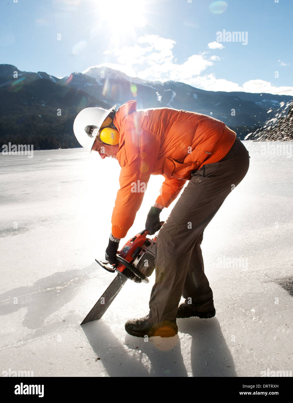 Ein Mann schneidet einem zugefrorenen See mit einer Kettensäge, Blöcke für einen Ice-Carving-Wettbewerb zu ernten. Whistler, BC, Kanada Stockfoto