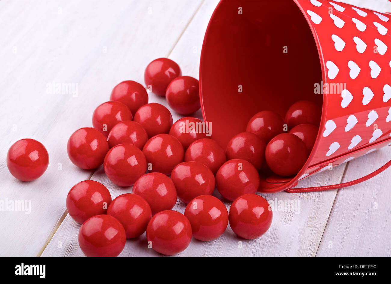 Bonbons für Valentine und dekorative Behälter auf einem hellen gemalten hölzernen Hintergrund Stockfoto