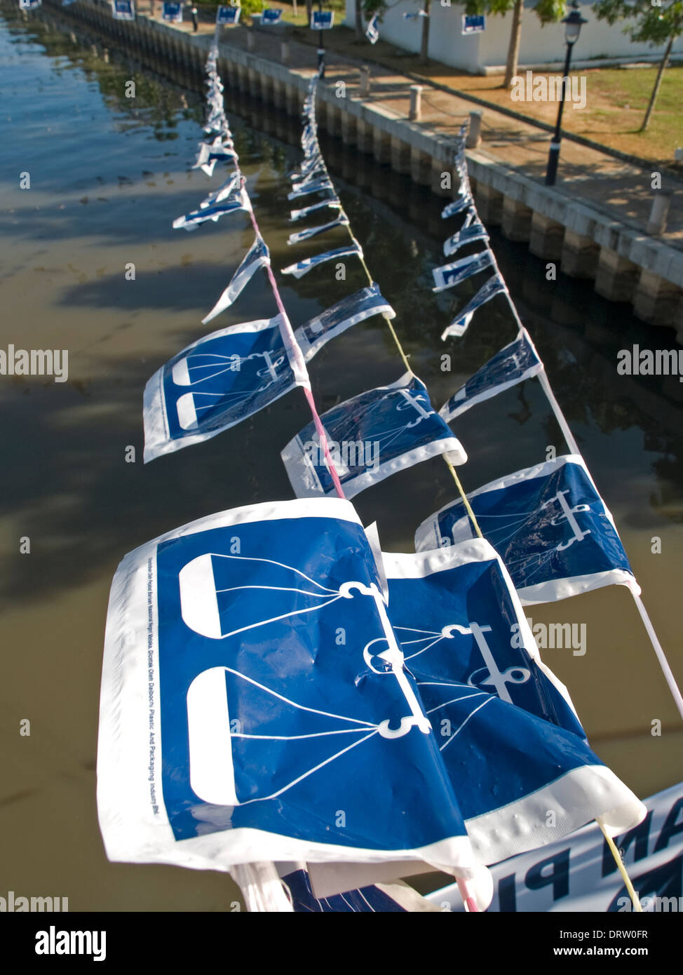 Kunststoff Fahnen mit den blau-weißen Schuppen Symbol der Barisan Nasional politische Partei über das Wasser Stockfoto