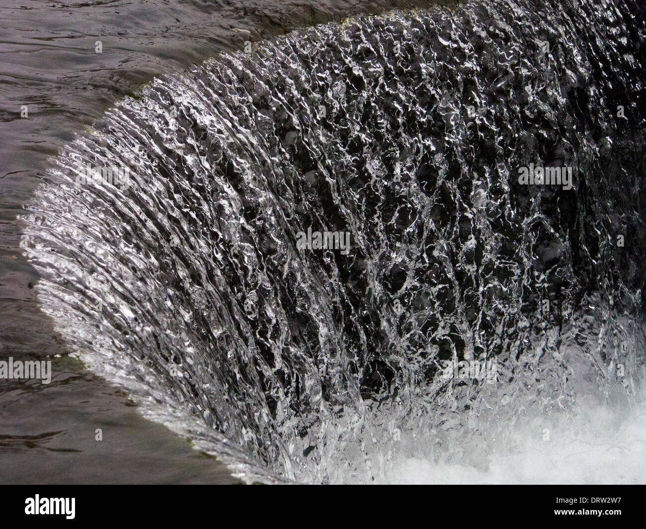 Wasser fällt über eine gebogene Wehr in den Mühlgraben im historischen Cromford Mill in Derbyshire Stockfoto