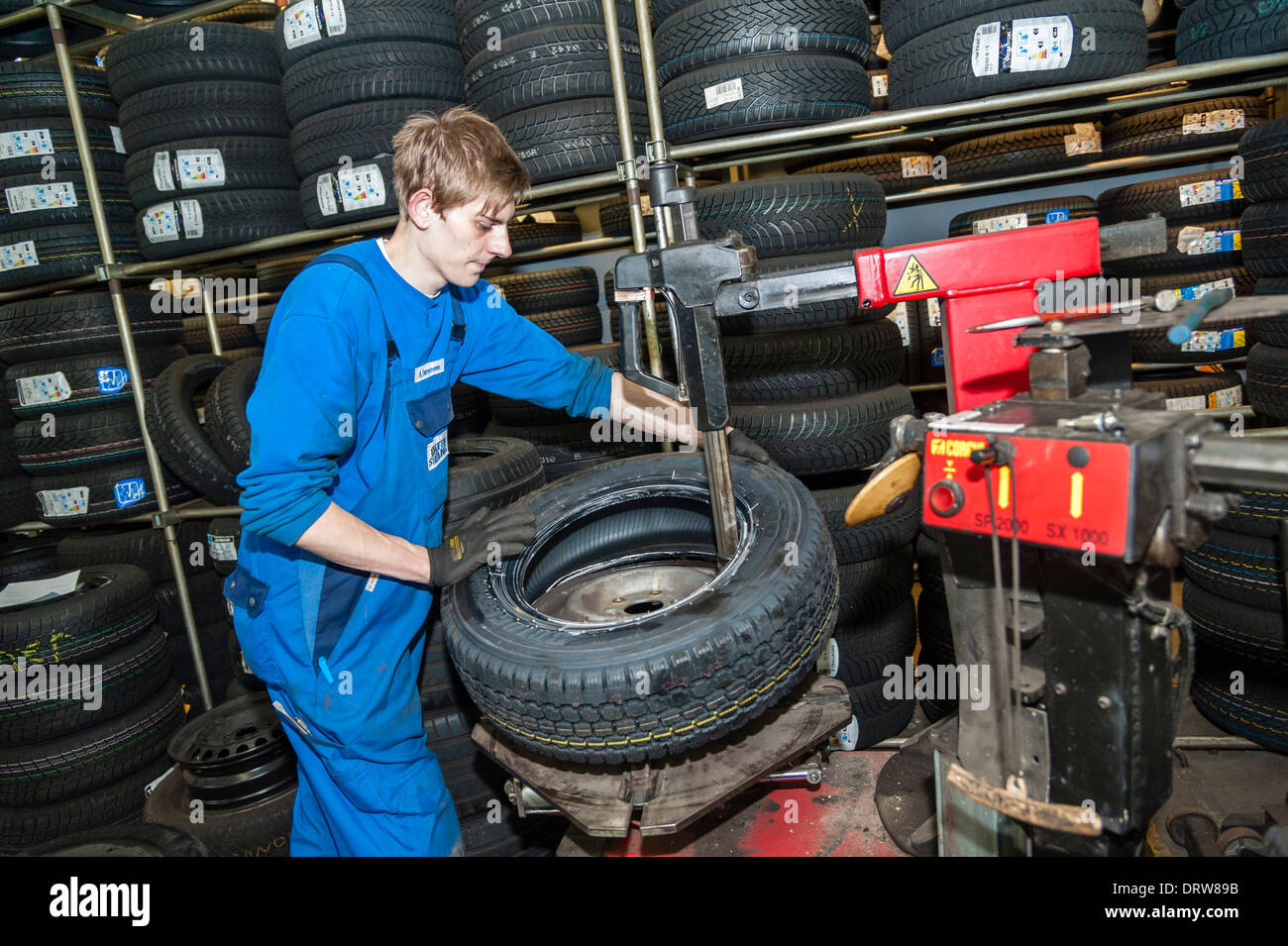 Kfz-Mechaniker passt einen neuen Reifen auf einer Felge. Stockfoto