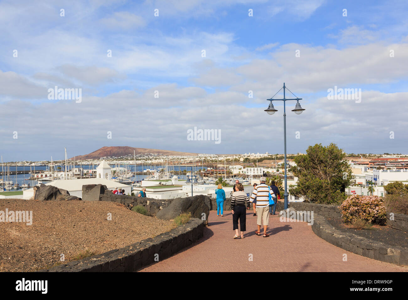 Menschen, die ein Spaziergang entlang der Strandpromenade promenade in gehobenen Resort Marina Rubicon, Playa Blanca, Lanzarote, Kanarische Inseln, Spanien Stockfoto