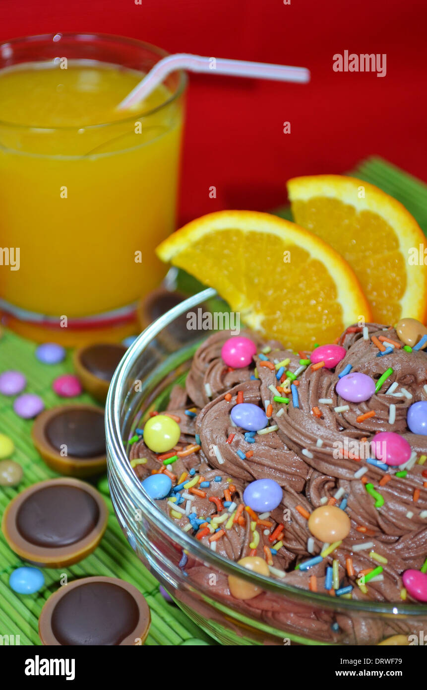 Mousse au Chocolat mit Stücken von Orange und Streusel und ein Glas Orangensaft Stockfoto