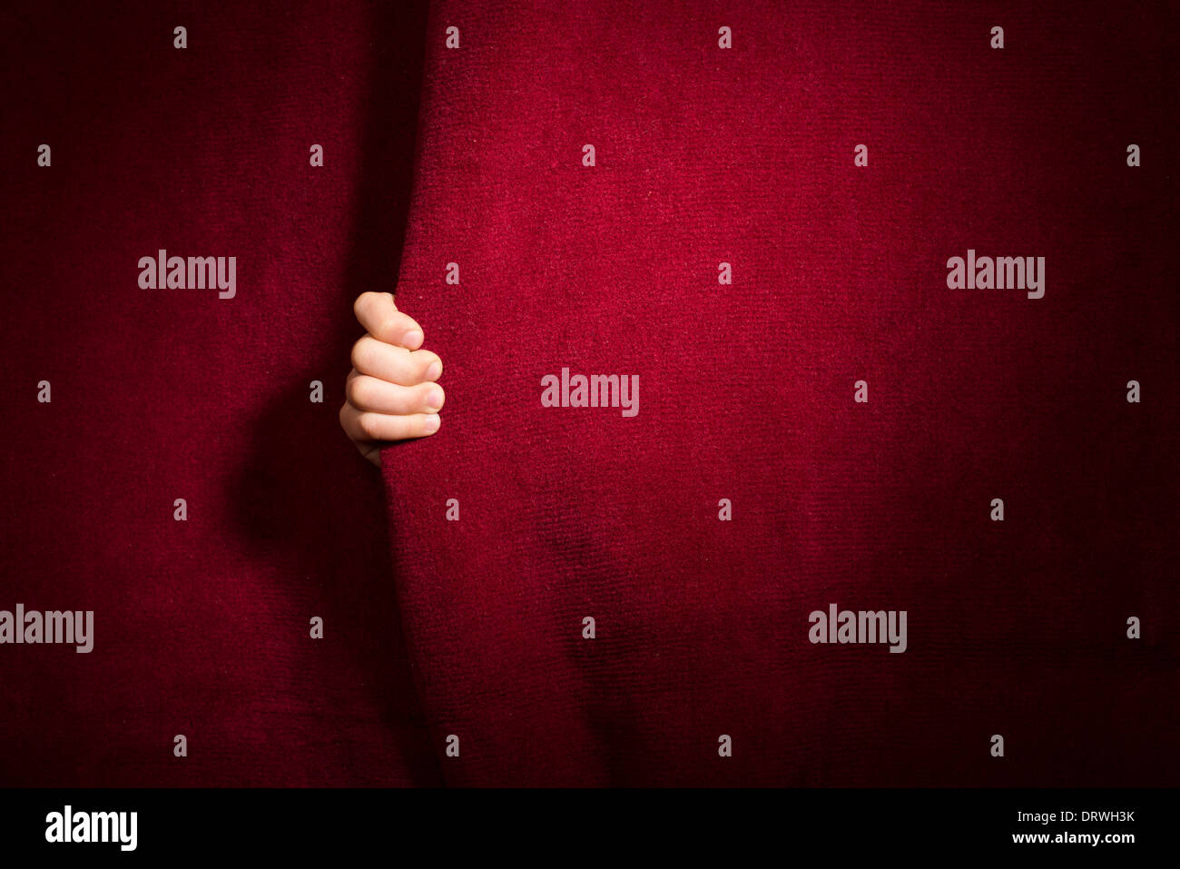 Hand unter dem Vorhang erscheinen. Roter Vorhang. Stockfoto