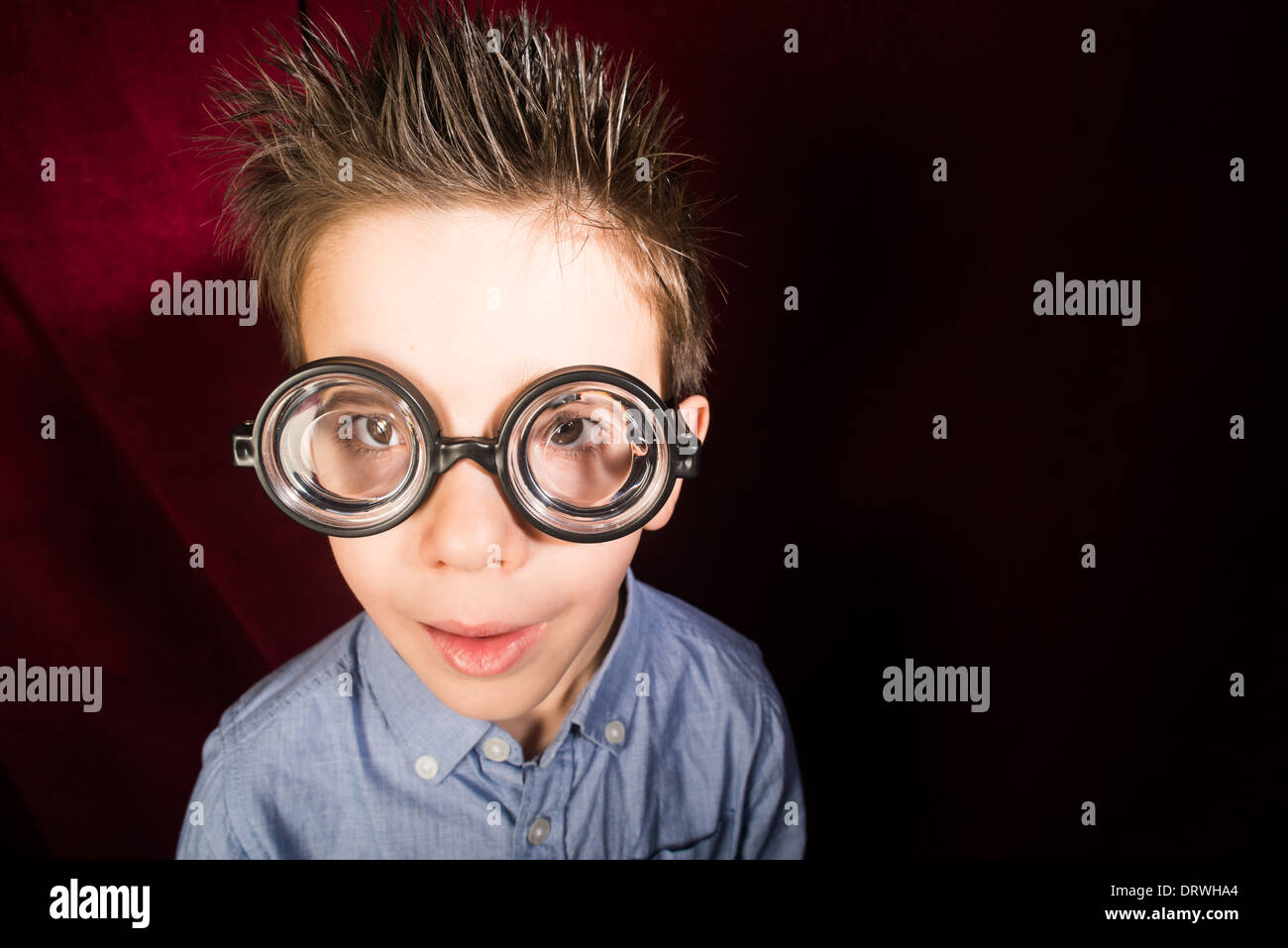 Lächelte Kind mit großen Gläsern. Roter Vorhang Hintergrund Stockfoto