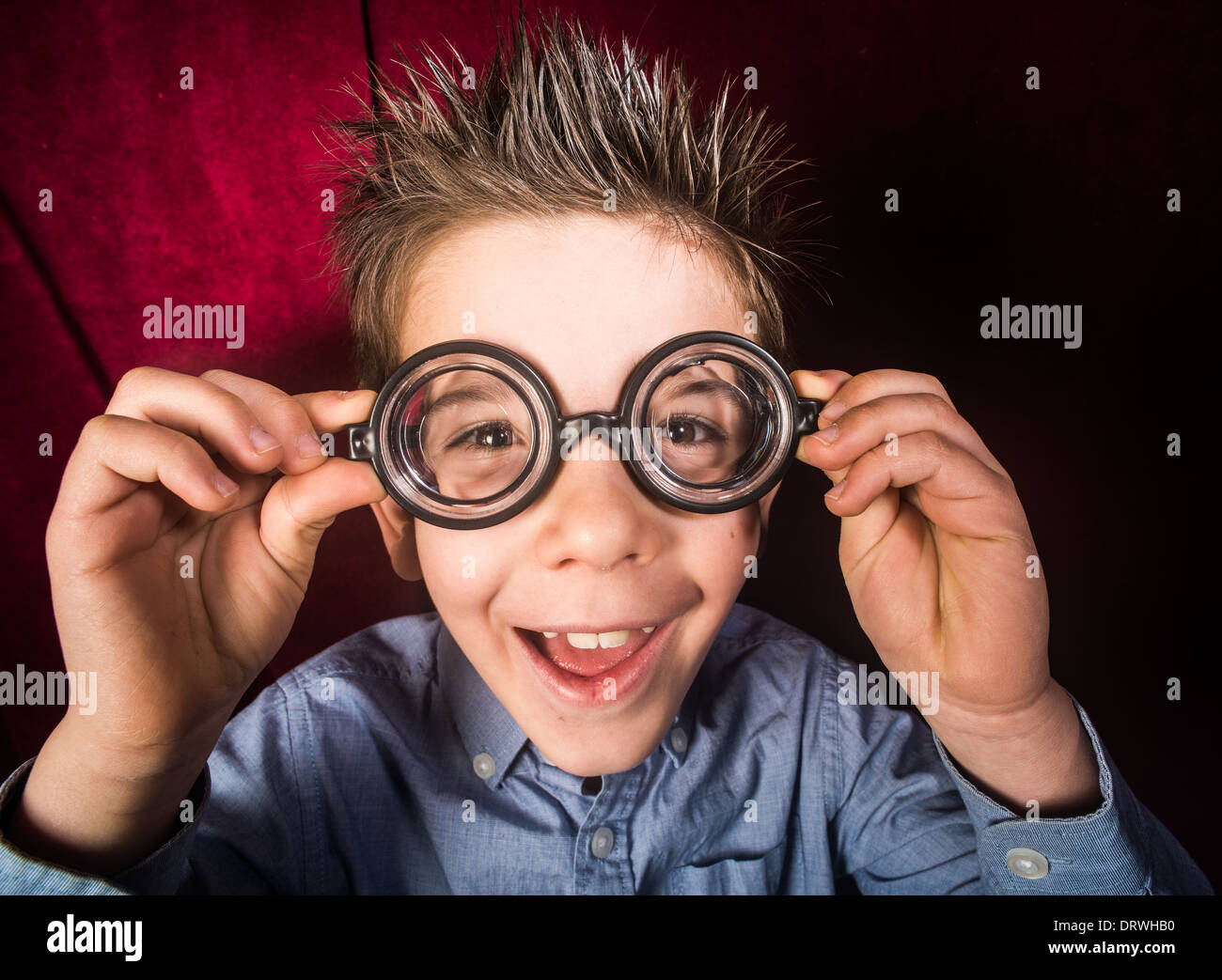 Lächelte Kind mit großen Gläsern. Roter Vorhang Hintergrund Stockfoto