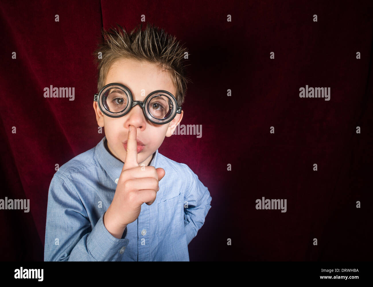 Kind mit großen Gläsern. Roter Vorhang Hintergrund Stockfoto