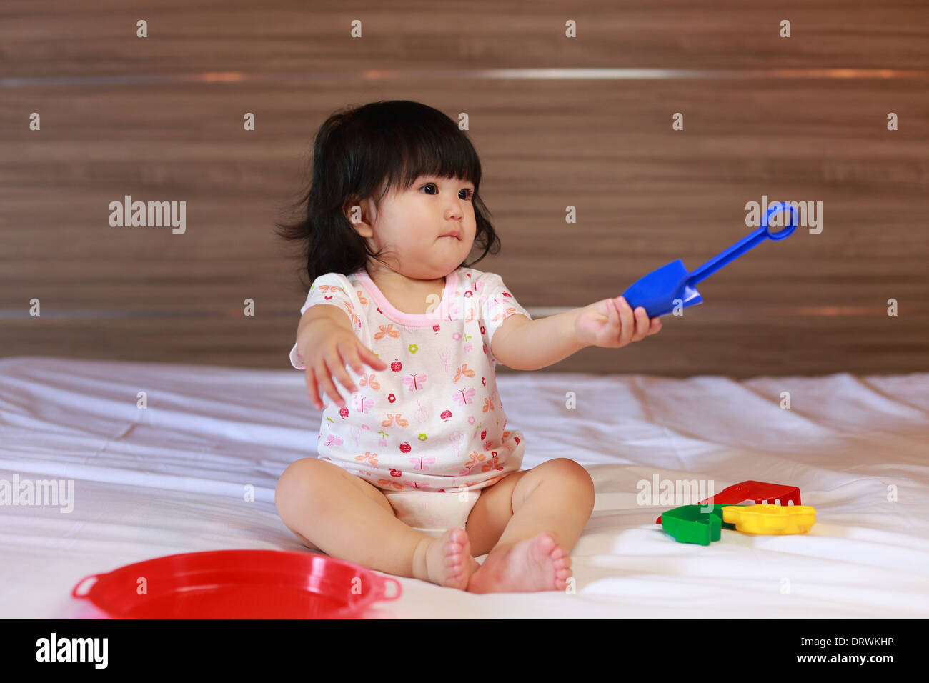 Baby girl Lernen, wie man mit bunten Kunststoff-Spielzeug spielen Stockfoto
