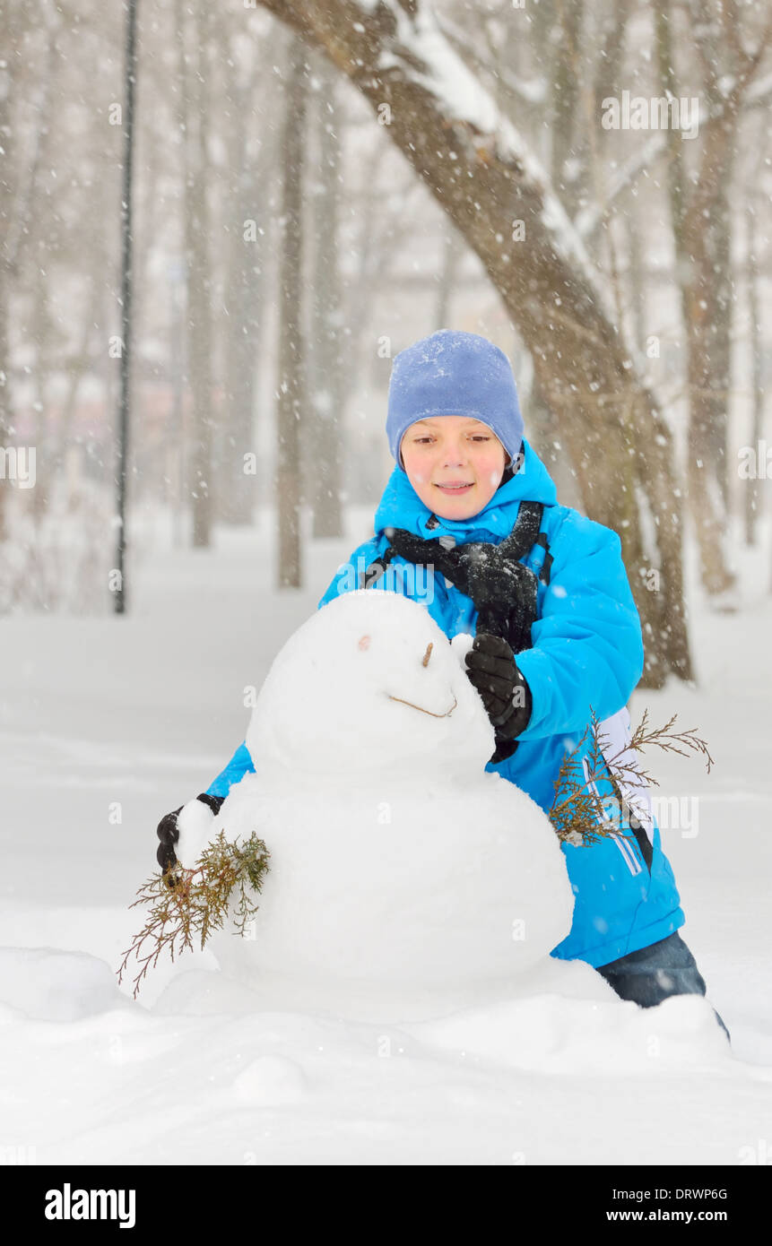 junge macht einen Schneemann im park Stockfoto